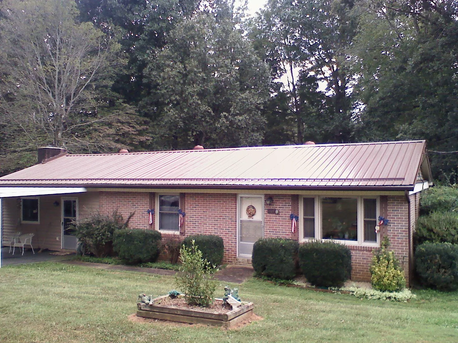 Bronze metal roof on a brick ranch home with a carport in Marion